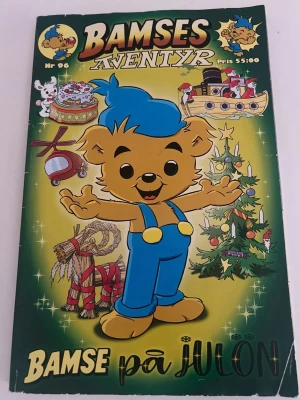 Bamses äventyr: Bamse på julen - En färgglad serietidning med Bamse på omslaget, klädd i blå mössa och hängselbyxor. Omslaget har julmotiv som julgran, pepparkakshus och julbock. Perfekt för dig som gillar klassiska svenska serier och julstämning.