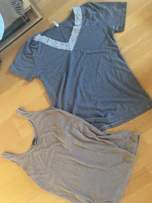 Gina Tricot Två grå toppar, spets och linne - Säljer två grå toppar. Ena är en kortärmad topp med v-ringning och spetsdetalj runt halsen. Den andra är en enkel, ärmlös linnetopp med rund hals. Båda är i mjukt material och passar perfekt till jeans eller kjol.