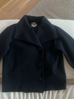 mörkblå kappa från Gina Tricot - Stilren mörkblå kappa från Gina Tricot med tre knappar framtill och bred krage. Lite nopprig men annars inga defekter, kontakta vid frågor eller fler bilder!