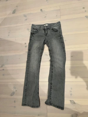 Grå jeans från Gina Tricot bootcut - Snygga grå jeans från Gina Tricot i storlek 164. Modellen har bootcut-ben, klassisk femficksdesign och dragkedjegylf. Jeansen har en tvättad look och är tillverkade i mjukt denimtyg som passar perfekt till vardagsstilen.