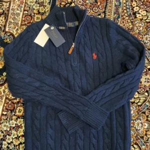 Mörkblå kabelstickad tröja från Ralph Lauren - Säljer en storlek S Ralph Lauren half zip. Den är knappt använd,har använt den i ca 2 veckor och den har varit för liten. Kan meddelas vid snabb affär