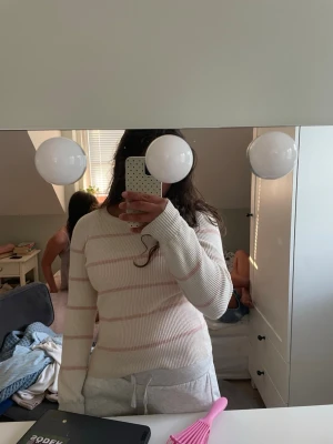 Vit stickad tröja med rosa ränder  - Säljer en söt vit stickad tröja med tunna rosa horisontella ränder. Tröjan har rund halsringning och långa ärmar. Perfekt för dig som gillar en enkel men stilren look. Är stor i storleken och passar mig som brukar ha storlek S i stickade tröjor. Skönt material och knappt använd. 