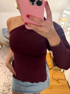 Vinröd oneshoulder topp - Snygg vinröd topp med oneshoulder-design och lång ärm på ena sidan. Från zara och knappt använd! 