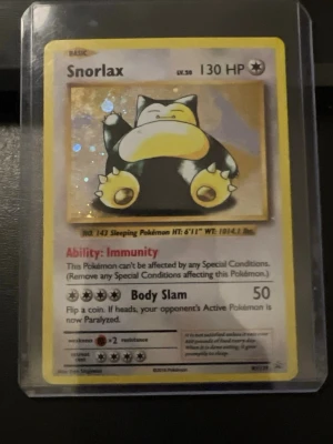 Snorlax Pokémonkort holografiskt - Säljer ett holografiskt Snorlax Pokémonkort med gul ram och klassisk design. Kortet har 130 HP och visar Snorlax i en avslappnad pose. Perfekt för samlare eller dig som vill uppgradera din kortlek.