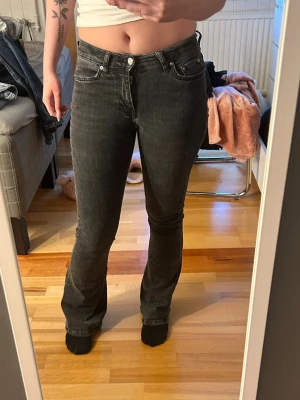 Svarta bootcut jeans med låg midja - Säljer ett par svarta bootcut jeans med låg midja och klassisk femficksmodell. Jeansen har en lätt utsvängd passform nedtill och är tillverkade i stretchigt denimtyg för skön känsla. Perfekta för dig som gillar en tidlös och trendig look.