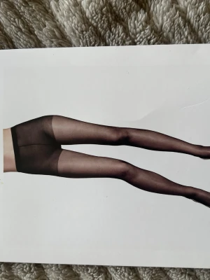 Svarta tunna strumpbyxor - Säljer ett par klassiska svarta tunna strumpbyxor med förstärkt tå. Perfekta till kjol eller klänning när du vill ha en stilren look. Materialet är elastiskt och följsamt för bästa passform.