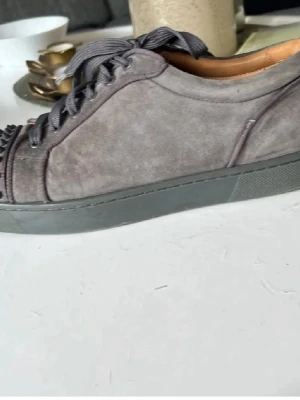 Gråa sneakers med nitar och röd sula - Hej säljer nu mina Loubs då jag har köpt andra skor. Dom är inte riktigt i samma kondition som dom är på bilderna det fattas typ 3 spikar eftersom jag körde kross med dom ett tag. Men det är inget man lägger mycket märket till. Jag har fått massa komplimanger om skorna och dom är väldigt stiliga o snygga. Perfekt till dig som försöker sticka ut lite o vara lite stilig samt ha en vardags sko.