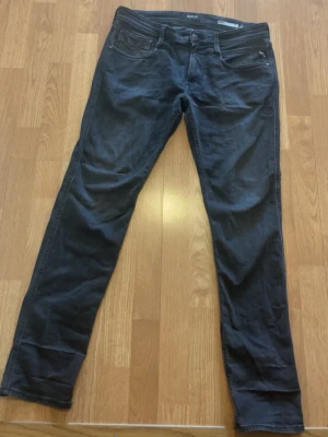 Svarta replay slim fit jeans - Säljer ett par svarta slim fit jeans med klassisk femficksdesign och dragkedja. Jeansen har smal passform och raka ben, perfekta för en stilren och enkel look. Materialet är mjukt och stretchigt för extra komfort.w32,L32