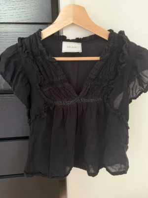 Svart blus med volang från Neo Noir - Super söt svart blus från neo noir, säljer då den inte kommer till användning 