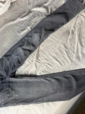 Grå slim fit jeans - Snygga grå slim fit jeans med klassisk femficksdesign och raka ben. Jeansen har en diskret tvättad look och är tillverkade i mjukt denimtyg som ger en skön passform. Perfekta för dig som gillar en stilren och enkel look.