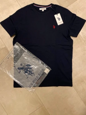 Ny U.S Polo Assn t-shirt - Hej! Säljer en snygg mörkblå t-shirt från U.S. Polo Assn. Den är i storlek L och är tillverkad i mjukt bomull. Helt ny och originalförpackning finns. Perfekt till sommaren för att finslipa din stil. Har även en likadan i storlek S vid intresse. Tveka inte att höra av dig vid frågor!