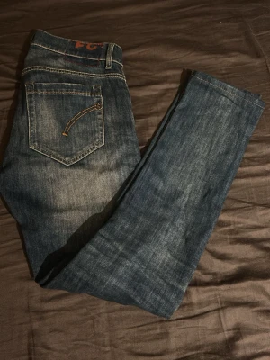 Dondups jeans blå  - Säljer ett par klassiska blå jeans med raka ben och snygga kontrastsömmar. Jeansen har en bakficka med dekorativ söm och en patch i midjan. Tillverkade i slitstarkt denim, perfekta till vardagslooken. Strl 31 