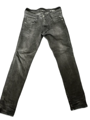 Svarta replay anbass - Snygga svarta slim fit jeans med klassiska fickor och dragkedjegylf. Jeansen har diskreta slitningar och raka ben. Perfekta för en avslappnad och trendig look. Materialet är troligtvis bomull med lite stretch för extra komfort. Modell: Anbass. Storlek: 30/32. Nypris: 1300kr. Mitt pris: 499kr.