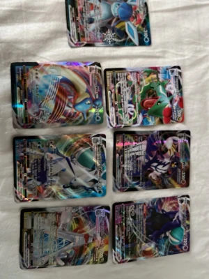 Pokémonkort Vmax samling - Säljer en samling med åtta Pokémonkort av typen EX och GX. Korten har färgstarka och holografiska motiv med olika Pokémon, bland annat drakar och legendariska figurer. Perfekt för dig som vill utöka din samling eller gillar att spela Pokémon TCG.