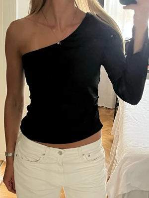 Svart oneshoulder topp - Snygg svart oneshoulder topp med lång ärm på ena sidan och axelbandslös på andra. Satinmaterial och använd ca 1 gång. Storlek S❣️