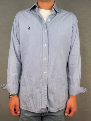 Ralph lauren skjorta randig M - Supersnygg randig ralph lauren skjorta. Size 15 1/2 som motsvarar M. Bredd: 45cm. Längd 70cm! Modellen är 180. Rekomenderad längd: 180-186cm. Fint skick. Hör av dig vid intresse 🤩