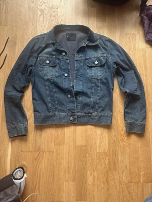 Mörkblå  jeansjacka från Sisley. - Säljer en mörkblå jeansjacka med raka sömmar och två bröstfickor med lock och knappar. Storleken passar S/M. 