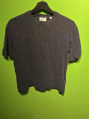 Mörkgrå t-shirt från GANT - En enkel och stilren mörkgrå t-shirt från GANT med diskret broderad logga på bröstet. Klassisk rund halsringning och korta ärmar. Tillverkad i mjuk bomull för skön känsla hela dagen.