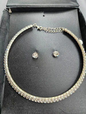 Glittrigt halsband & örhängen Montini - Säljer ett set från Montini med ett gnistrande halsband och matchande örhängen. Båda är silverfärgade och täckta med små klara stenar som ger en riktigt lyxig känsla. Perfekt till dig som vill ha något extra till din outfit.  Dock är förpackningen platt och lite skadad  Kan även hämtas I Partille  J