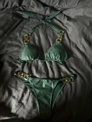Grön bikini med gulddetaljer - Snygg grön bikini med ormmönster och guldfärgade ringdetaljer på både överdel och underdel. Helt ny, storlek S 