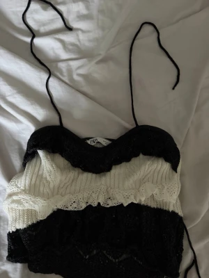 Svartvit stickad linnetopp från Zara - Supersöt stickad linnetopp från Zara i svart och vitt. Toppen har smala knytband och en vågig, virkad look med olika stickade mönster. Perfekt att styla med jeans eller kjol för en trendig vibe.