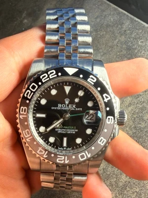 Rolleee gmt-master bruuccee wayynnee -  Rolllee GMT-Master bruce wayynnee med  silverfärgat jubilee armband i rostfritt stål.  Lite smutsig på bilden. Klockan är helt ny inga repor.