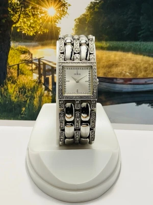 Silverfärgad klocka från Guess - Stilren och glittrig klocka från Guess i silverfärg med fyrkantig urtavla. Armbandet har stora länkar och är dekorerat med gnistrande stenar runt både urtavlan och länkarna. Perfekt accessoar för dig som gillar att sticka ut med detaljer. Längd 16,5cm, bredd 2,1cm, nyligen bytt batteri, säljes i befintligt skick enligt bilderna!