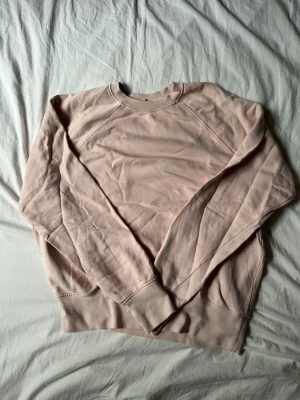 ARKET sweatshirt  - En stilren ljusrosa sweatshirt i extra långfibrig bomull. Tröjan har rund halsringning, långa ärmar och ribbade muddar vid ärmslut och nederkant. Perfekt för en avslappnad och trendig look.