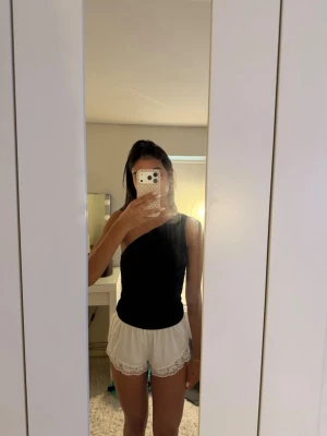 Svart oneshoulder topp - Säljer en svart oneshoulder topp med tight passform. Toppen är ärmlös på ena sidan och har en asymmetrisk skärning som ger en trendig look. Perfekt att styla med både jeans och kjol för en cool outfit❣️