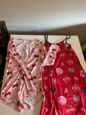 Szexy sleep time - Säljer två pyjamasar: en rosa långärmad med körsbärsmönster storlek S och en röd nattlinne med tunna axelband storlek Moch tryck av donuts och bakverk. Båda är i mjukt, stretchigt material och perfekta för mysiga hemmakvällar.