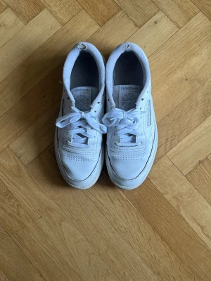Vita Reebok Club C 85 sneakers - Klassiska vita Reebok Club C 85 sneakers med lågt skaft. Har använts under 2025 men är tvättade. 