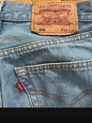 Levi's 501 ljusblå raka jeans - Klassiska Levi's 501 jeans i ljusblå denim med raka ben och medelhög midja. Jeansen har fem fickor, gylf med knappar och den ikoniska röda Levi's-lappen på bakfickan. Passar mig som är 170 lång typ.