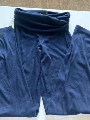Mörkblå yogapants från Gina Tricot - Mörkblå leggings från Gina Tricot i ribbat stretchigt material. Hög midja med bred linning som kan vikas ner för en avslappnad look. Perfekta att matcha med oversized tröjor eller hoodies.