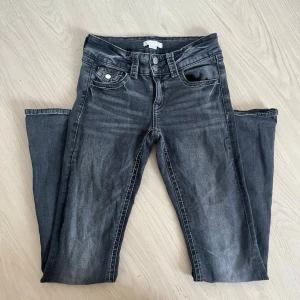 Grå jeans från Gina Tricot - Säljer ett par grå jeans från Gina Tricot i storlek 158. Jeansen har klassisk femficksmodell, raka ben och snygga slitningar framtill. Silverfärgade knappar och detaljer. Perfekta för en avslappnad och trendig look.