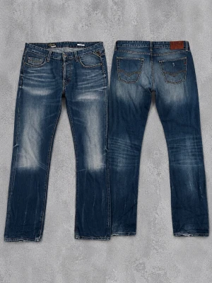 Blå Replay jeans med slitningar - Snygga blå jeans från Replay med coola slitningar och ljusa partier framtill och baktill. Klassisk femficksmodell med raka ben och läderpatch med Replay-logga bak i midjan. Perfekta för en avslappnad och trendig stil.
