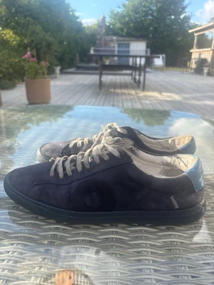 Mörkblå Oliver Cabell  sneakers med vita snören - Snygga mörkblå sneakers i mocka med vita snören och en ljusblå detalj på hälen. Skorna har en klassisk låg profil och svart sula. Perfekta för dig som gillar stilrena och tidlösa sneakers.