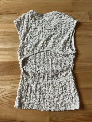Beige ribbad topp med öppen rygg - Trendig beige topp i ribbat material med unik öppen ryggdetalj. Toppen är ärmlös och har en smickrande, figurnära passform. 