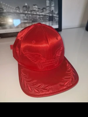 Röd satin keps med brodyr - Perfekt för dig som vill sticka ut med en unik accessoar. Inköpt I New York. 