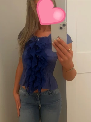 Blå blus med volanger framtill - Supersnygg blå somrig blus med korta ärmar och stora volanger längs hela framsidan. 💙💙🌸🌸pris kan diskuteras. Passar xs och s. 