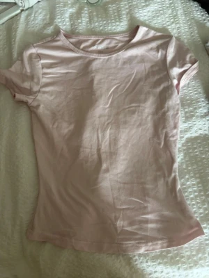 Ljusrosa t-shirt från SHEIN - Säljer en enkel och stilren ljusrosa t-shirt från SHEIN i storlek XXS. T-shirten har korta ärmar, rund halsringning och är gjord i ett mjukt material som känns skönt mot huden. Perfekt att matcha med jeans eller kjol.