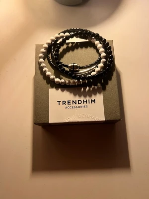 Svart och vitt armband från Trendhim - Stilrent armband från Trendhim med svarta och vita pärlor samt flätat svart läder🤩Snygg kombination av material och färger som ger en modern look. Perfekt accessoar för att lyfta din outfit.👏(OBS) Säljer inte styck, alla för 300kr, Ny pris 600kr
