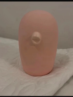 Cooee design figur - En unik rosa keramikfigur med rund form och en liten näbb framtill. Figuren har en minimalistisk design och är helt slät utan detaljerade drag. Passar som dekoration eller prydnad i hemmet.