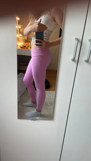 Rosa sömlösa leggings gymshark - Säljer ett par rosa sömlösa leggings med vikbar midja och tight passform. Materialet är stretchigt och mjukt, perfekt för träning eller chill. Snygg ribbad detalj vid midjan och längs benen. Passar dig som gillar färgglada och bekväma plagg. Perfekta till gymmet, pris kan diskuteras