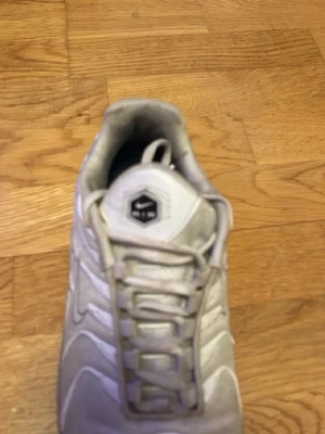 Vita Nike Air Max sneakers - Snygga vita Nike Air Max sneakers med synliga luftbubblor i sulan och meshdetaljer på ovandelen. Skorna har klassisk snörning och en sportig vibe, perfekta för dig som gillar streetwear. Hexagonlogga på plösen och vågformade paneler på sidorna.