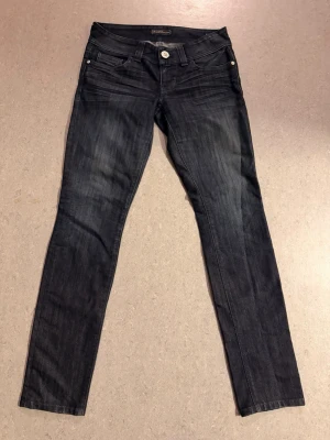 Mörkblå  straight jeans från Guess - Snygga mörkblå straight jeans från Guess med klassisk femficksmodell och silverfärgade detaljer. Jeansen har en smal passform och är tillverkade i stretchigt denimtyg för extra komfort. Perfekta till en avslappnad streetstyle-look.