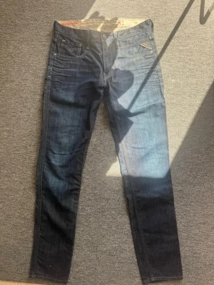 Mörkblå raka jeans herr - Snygga mörkblå jeans med raka ben och klassisk femficksmodell. Jeansen har en diskret tvättad look och detaljer i kontrastsömmar. Tillverkade i denim med en något stretchig känsla för extra komfort. Passar perfekt till en avslappnad stil.