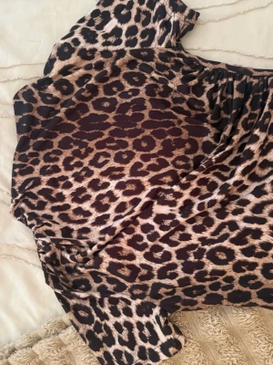 Leopardmönstrad kort tröja - Säljer en snygg kort klänning med leopardmönster. Klänningen har korta ärmar och är gjord i ett mjukt, stretchigt material som känns skönt mot huden. Perfekt för dig som vill sticka ut med ett djuriskt print.