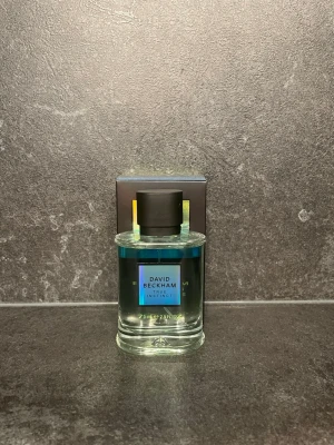David Beckham Instinct parfym 75 ml - Fräsch parfym från David Beckham med blågrön vätska i en rund, genomskinlig glasflaska. Flaskan har svart lock och en stilren etikett framtill. Förpackningen är mörk med diskreta detaljer. Volymen är 75 ml.