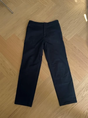Mörkblå raka chinos från Filippa kr - Snygga mörkblå chinos med rak passform och klassisk design. Byxorna har diskreta fickor bak och framtill samt dold dragkedjegylf. Har även dragsko i midjan för bra passform. Tillverkade i ett mjukt och bekvämt bomullsmaterial som passar perfekt till en avslappnad men stilren look.