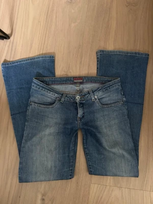 Blå bootcut jeans från Big Star - Säljer ett par klassiska blå bootcut jeans från Big Star. Jeansen har fem fickor och låg midja.  Tillverkade i slitstarkt denim med kontrastsömmar och knappgylf. Perfekta för en avslappnad och trendig look.